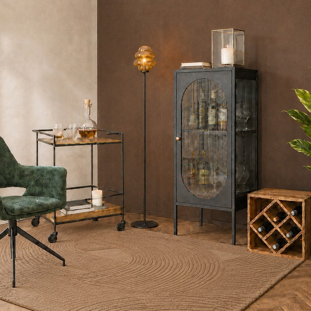 Coin bar avec fauteuil en velours vert, chariot de bar noir, vitrine à verre strié et lampadaire ambré