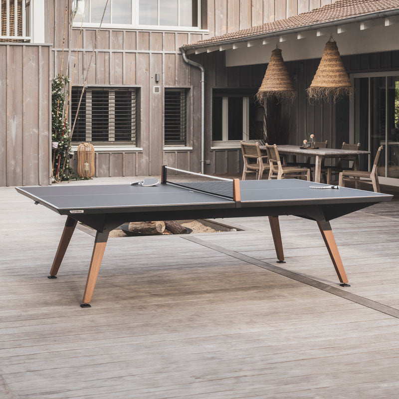 Table de ping-pong Cornilleau Origin outdoor installée sur la terrasse d'une maison en bois