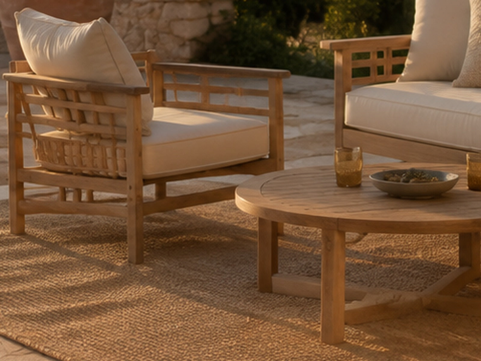 Fauteuils en teck avec coussins écrus sur une terrasse en pierre