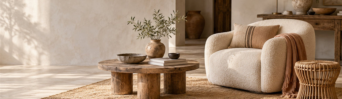 Fauteuil en bouclette, table basse ronde en bois et tabouret en rotin sur un tapis en jute – Mobilier J-Line