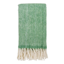 Plaid Carmel en laine verte sur un canapé, texture douce et élégante
