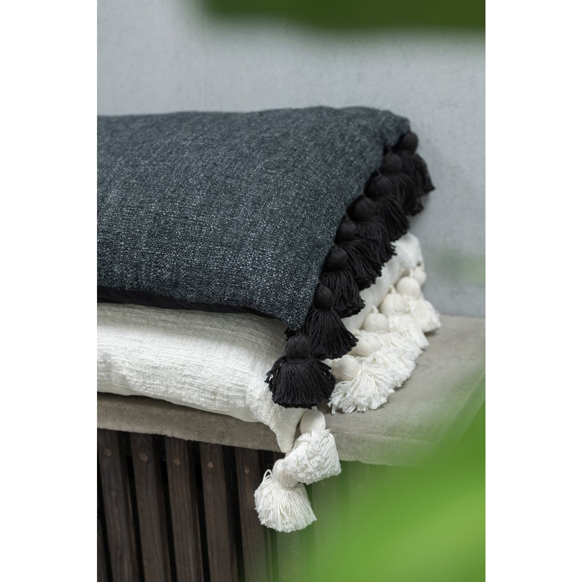 Coussin J-Line Pompon noir, mise en scène sur un canapé moderne.