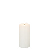 Bougie LED J-Line blanche allumée sur une table en bois