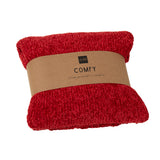 Couverture J-Line rouge drapée sur un canapé, ajoutant une touche de chaleur.