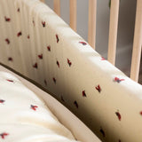 Tour de lit Lucky OYOY Living Design avec motif coléoptère rouge sur fond blanc cassé.