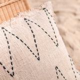 Coussin PITU en coton naturel sur un lit élégant