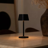 Lampe de table noire Ava allumée, montrant ses différents modes d'éclairage.