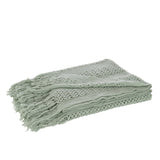 Plaid tricoté J-Line vert clair sur canapé, ambiance cosy