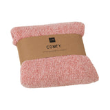 Couverture J-Line rose drapée sur un canapé moderne.
