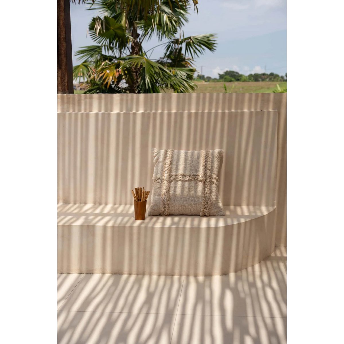 Housse de coussin Nomade sur un lit avec des draps clairs