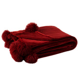Plaid Pompon J-Line drapé sur un canapé, ambiance chaleureuse