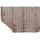 Plaid Vague Taupe drapé sur un fauteuil élégant, ajoutant une touche de luxe.