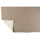 Plaid J-Line gris posé sur un lit avec coussins assortis