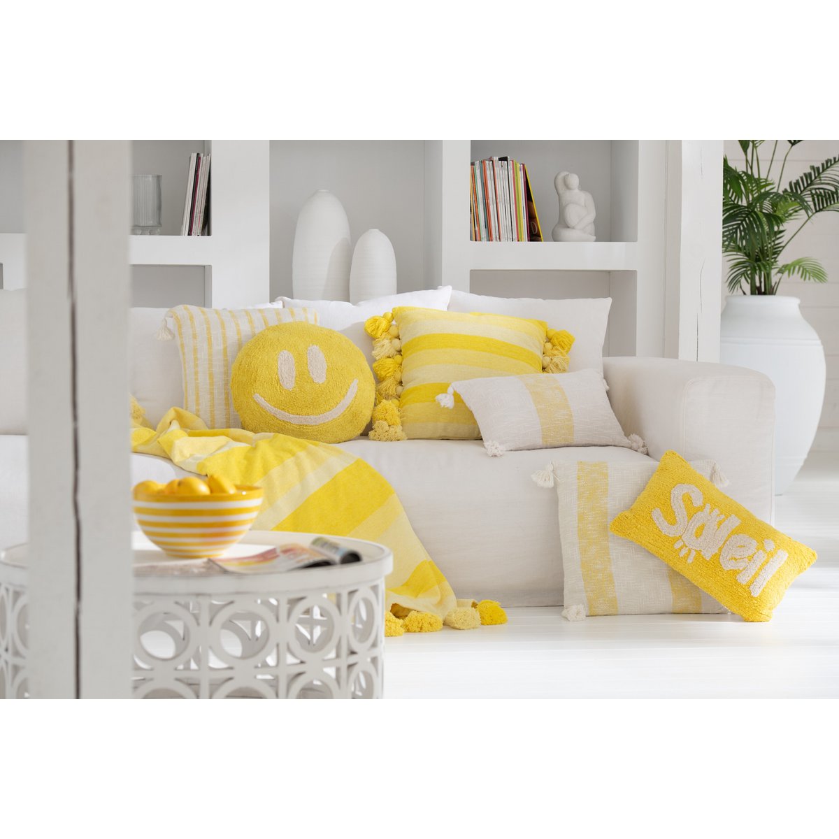 Coussin Soleil sur un lit décoré, illustrant son usage dans une chambre.