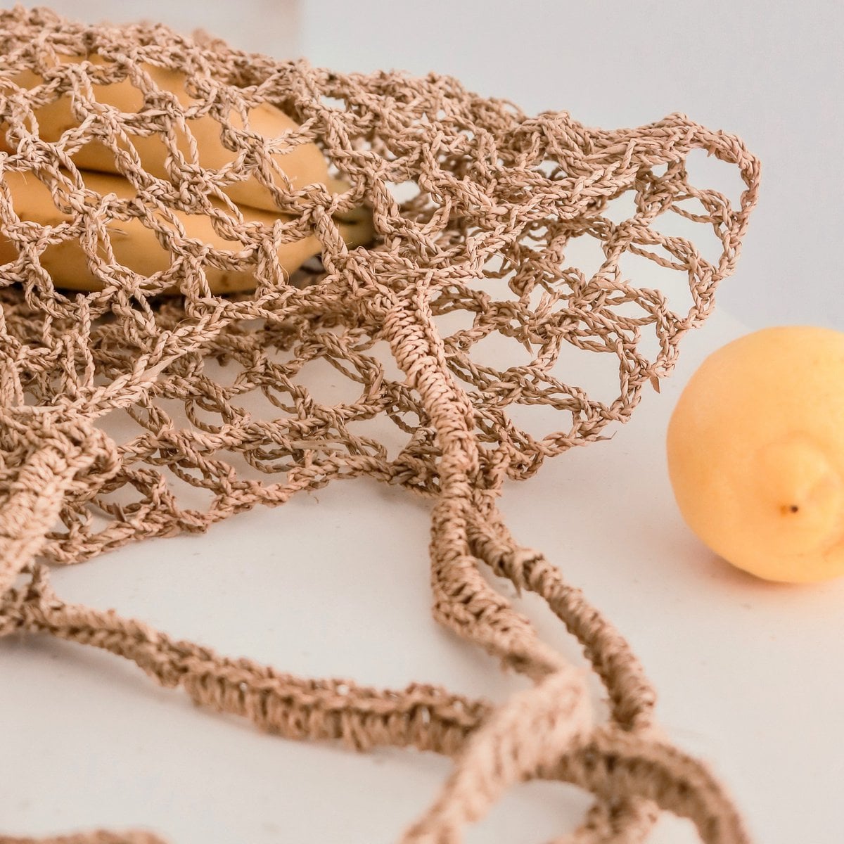 Détail des poignées du sac en raphia, design élégant et pratique