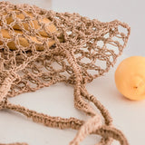Détail des poignées du sac en raphia, design élégant et pratique