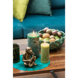 Bougie cylindrique J-Line vert foncé posée sur une table en bois