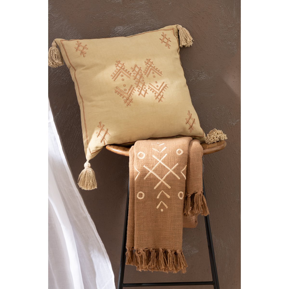 Plaid J-Line en coton marron sur un lit décoré, style boho.