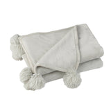 Plaid Pompon J-Line en polyester gris clair sur un canapé