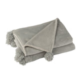 Plaid pompon gris J-Line sur un canapé moderne