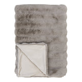 Plaid Galena en fourrure artificielle beige, posé sur un canapé pour un style cosy