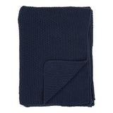 Plaid Santos en coton recyclé bleu sur un canapé moderne