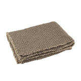 Plaid J-Line taupe drapé sur un canapé, ambiance cosy